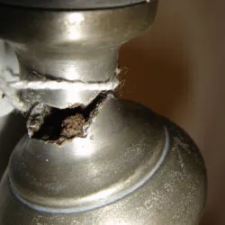 Close-up of the broken, torn pewter at the base of the candlestick stem
